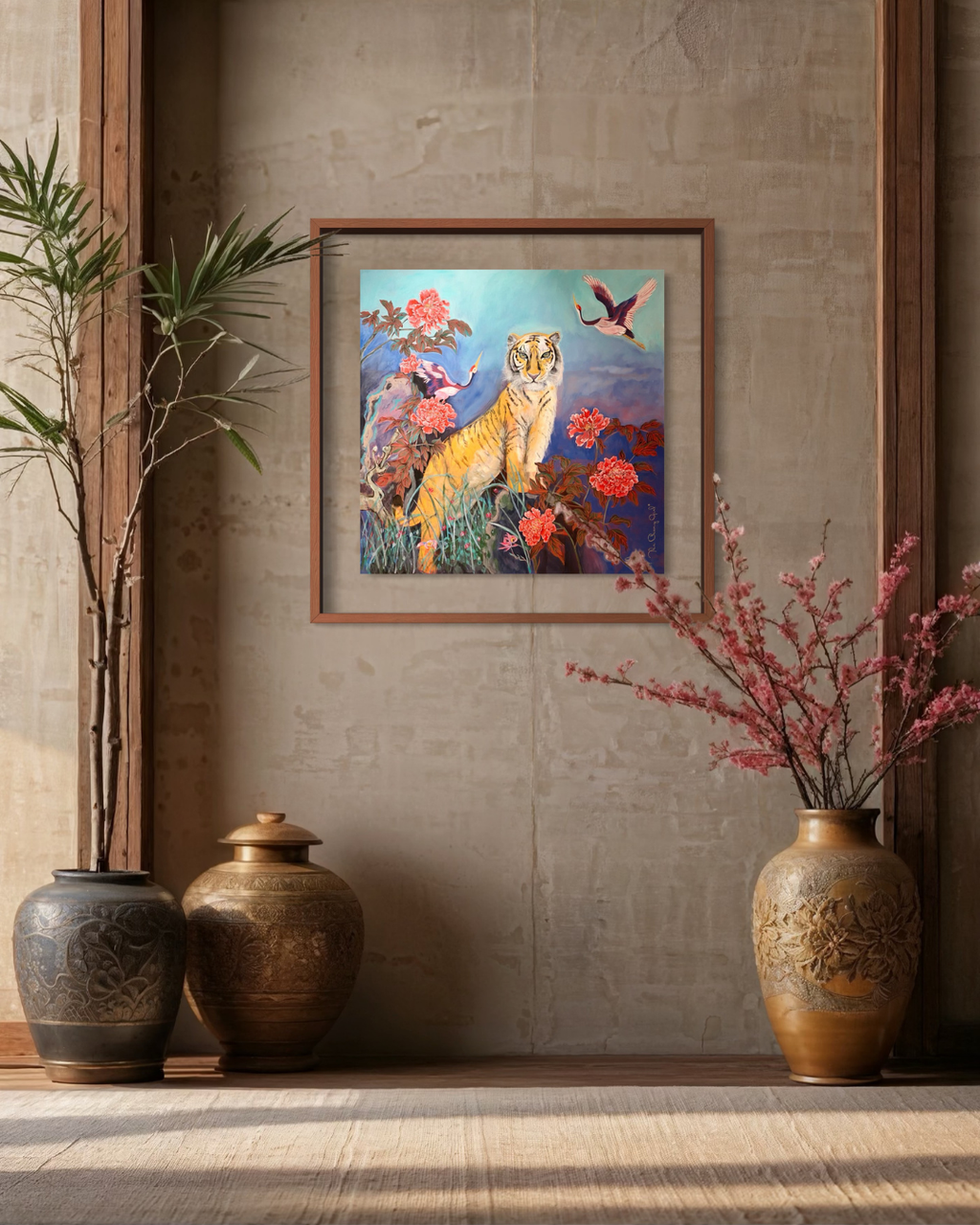 A framed art print depicting a golden tiger surrounded by pink flowers and birds, displayed on a textured beige wall above a wooden floor, flanked by decorative ceramic vases and a potted plant.
