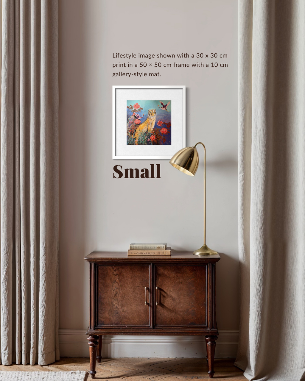 A framed art print displayed on a beige wall in a styled room setting, featuring a small wooden cabinet, a brass table lamp, and beige curtains. The print depicts a colorful underwater scene with a fish.