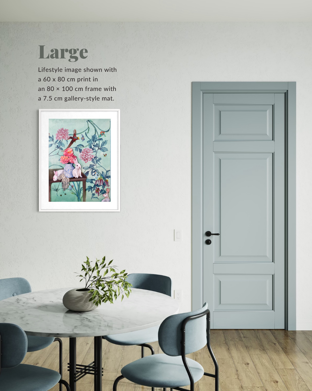 A framed art print featuring a colorful illustration of a bird perched on a tree, displayed on a light gray wall in a dining room setting next to a paneled door.