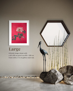 A framed wall art print featuring a pink floral design on a red background, displayed in a styled interior scene with a hexagonal mirror, a black crane sculpture, rocks, and decorative bamboo. Text on the image reads 'Large' and describes the print size and frame details.