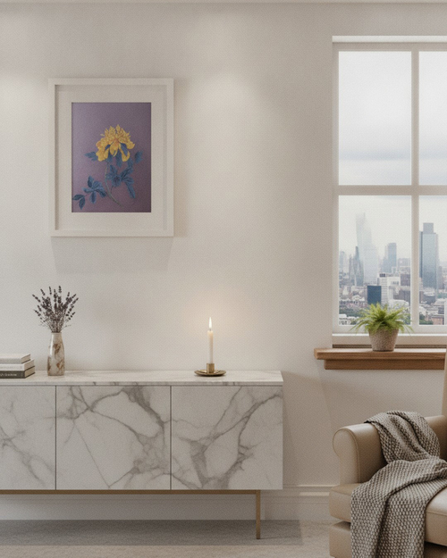 A framed floral art print with yellow flowers and blue leaves on a purple background, displayed on a cream wall above a marble-patterned sideboard in a modern living room setting.