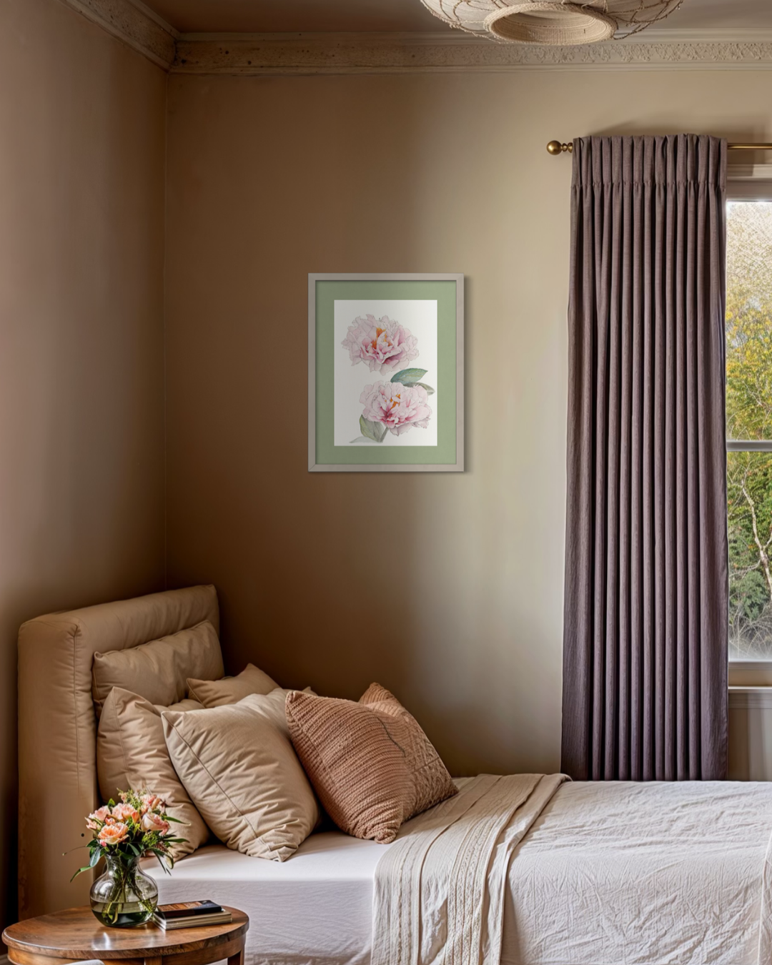 A styled bedroom interior featuring a bed with beige and brown pillows, a small wooden side table with flowers, a window with pleated taupe curtains, and a framed floral print on the wall.
