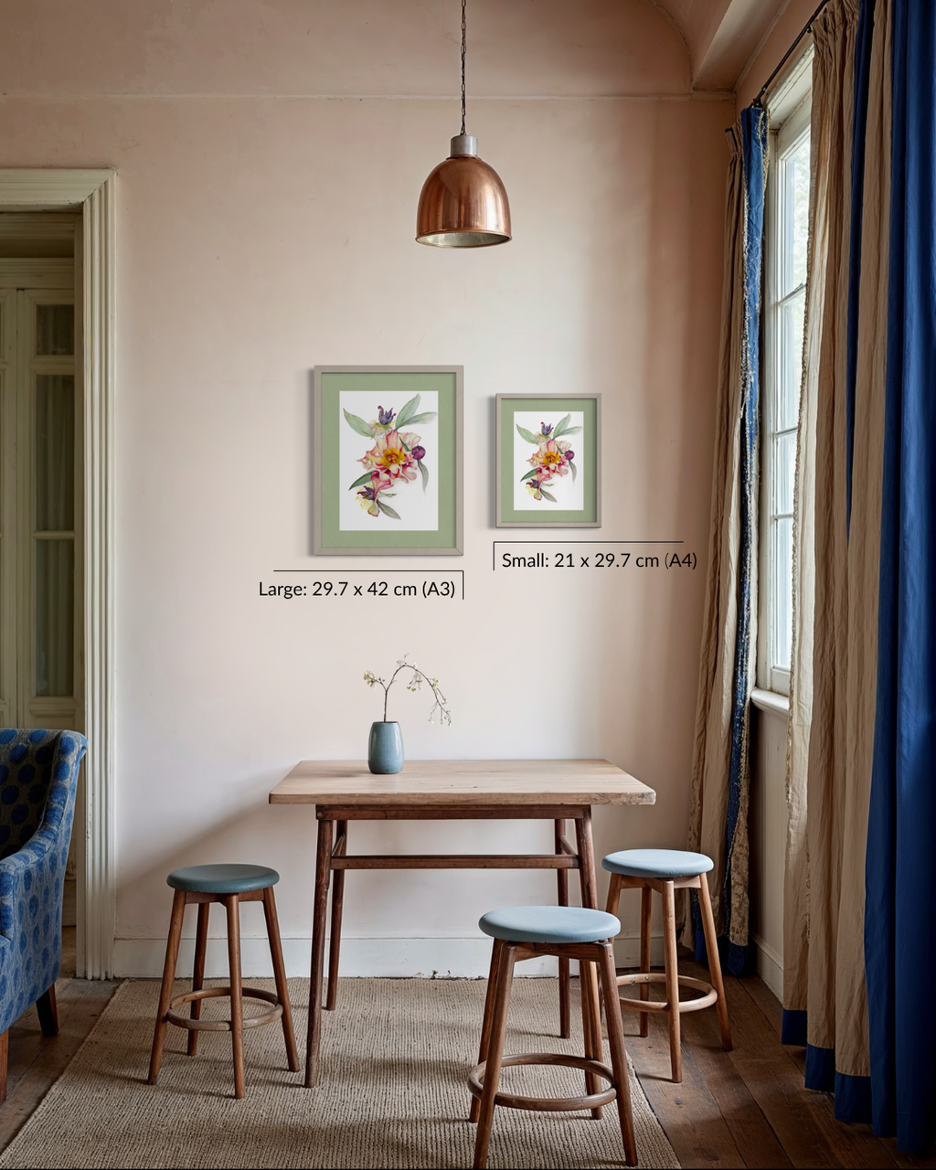 A styled interior room showing two framed botanical art prints on a beige wall above a small wooden table and stools. The prints are labeled as large 29.