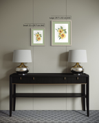 Two framed floral art prints displayed on a beige wall above a dark wood console table with two silver lamps. The image includes size labels for the prints: Small 21 x 29.