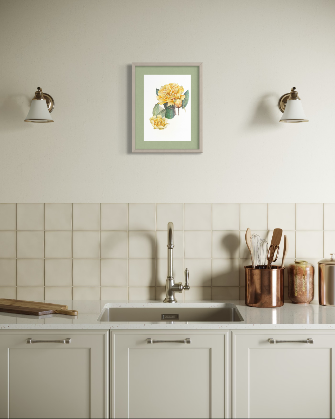 A framed botanical art print featuring yellow flowers and green leaves, displayed on a kitchen wall above a sink with white cabinets, a tiled backsplash, and copper kitchen utensils.