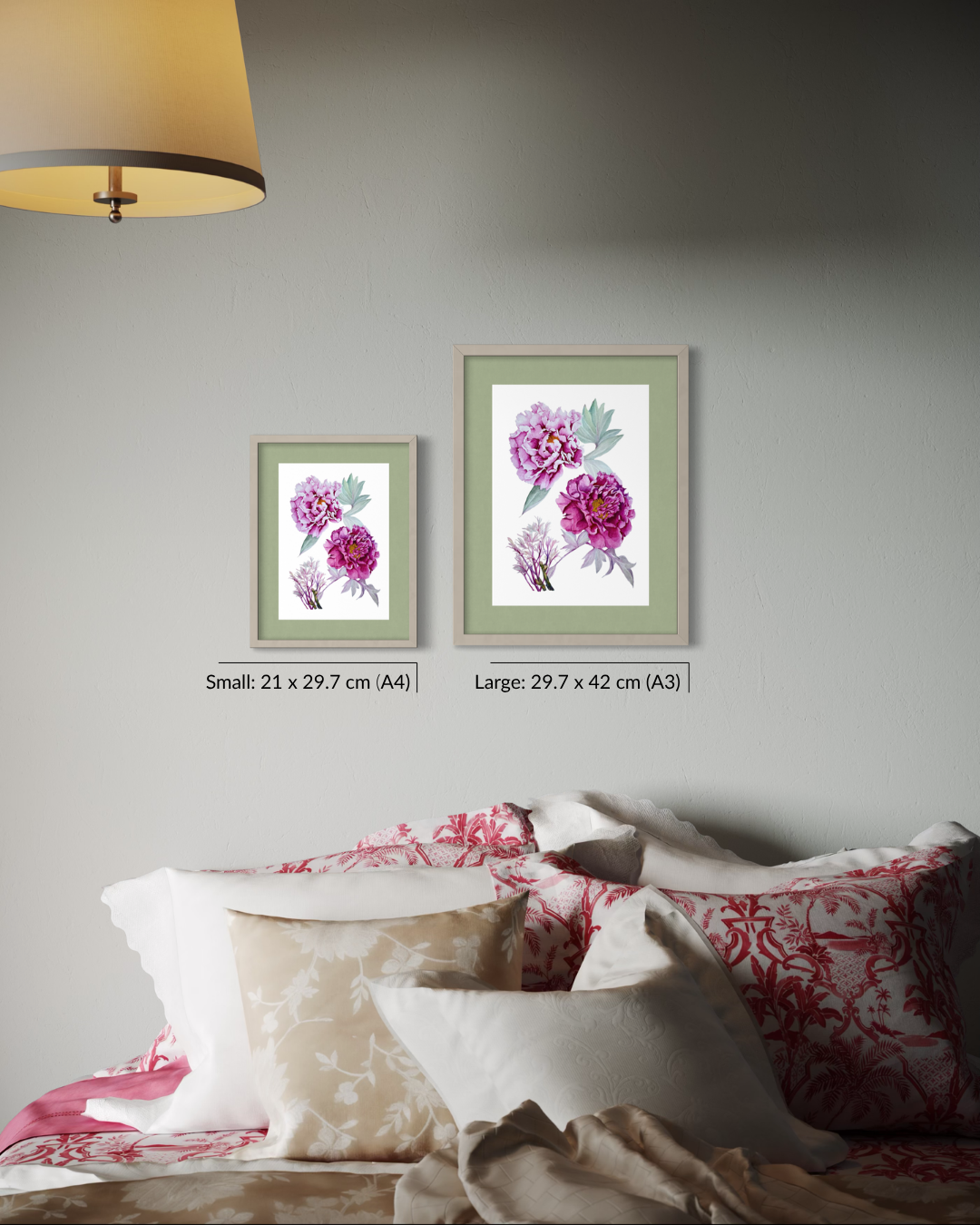 Two framed botanical art prints with pink and purple flowers hang on a light gray wall above a bed with patterned pillows. The larger print is labeled 29.