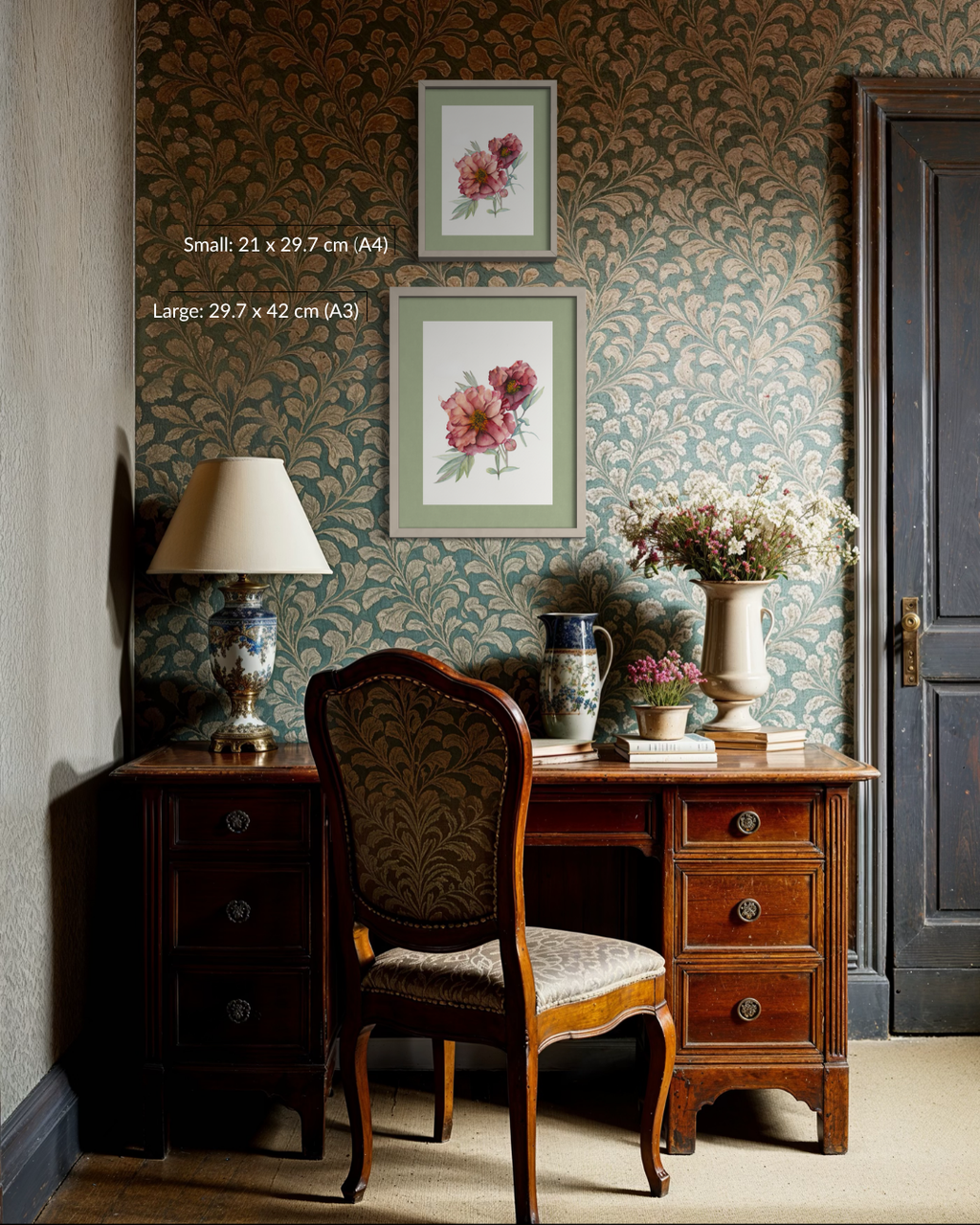 A styled interior scene showing a wooden writing desk with a matching upholstered chair, a table lamp, vases, and framed floral wall art against a patterned wallpaper background. White text on the left reads size information for the framed prints.