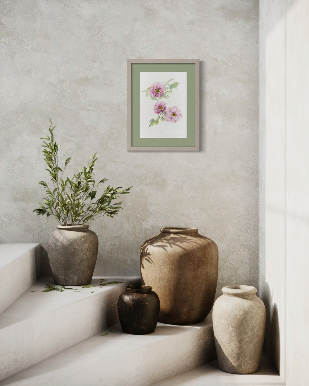 A framed botanical art print featuring pink flowers and green leaves, styled on a textured light gray wall above rustic ceramic vases on a stone staircase.