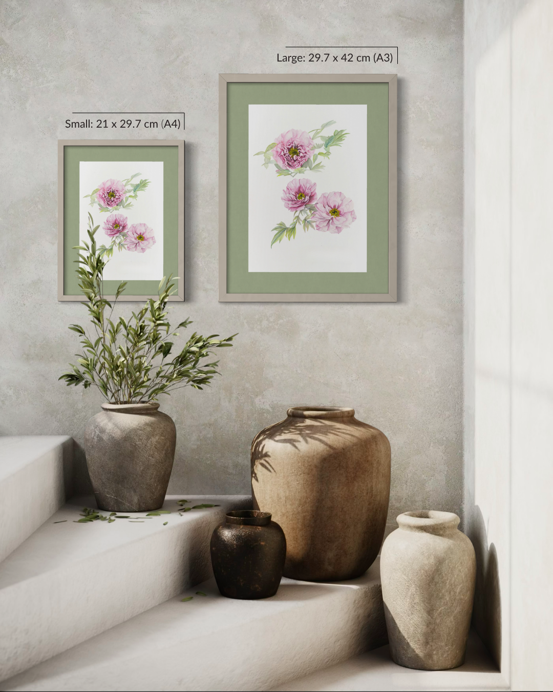 Two framed floral art prints hang on a textured light gray wall above a styled arrangement of ceramic vases. The larger print reads 'Large: 29,7 x 42 cm (A3)' and the smaller reads 'Small: 21 x 29,7 cm (A4)'.