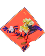 A square scarf laid flat in a diamond orientation, featuring a bright orange background with a large floral print in yellow, white, and deep purple, finished with a thin dark border.