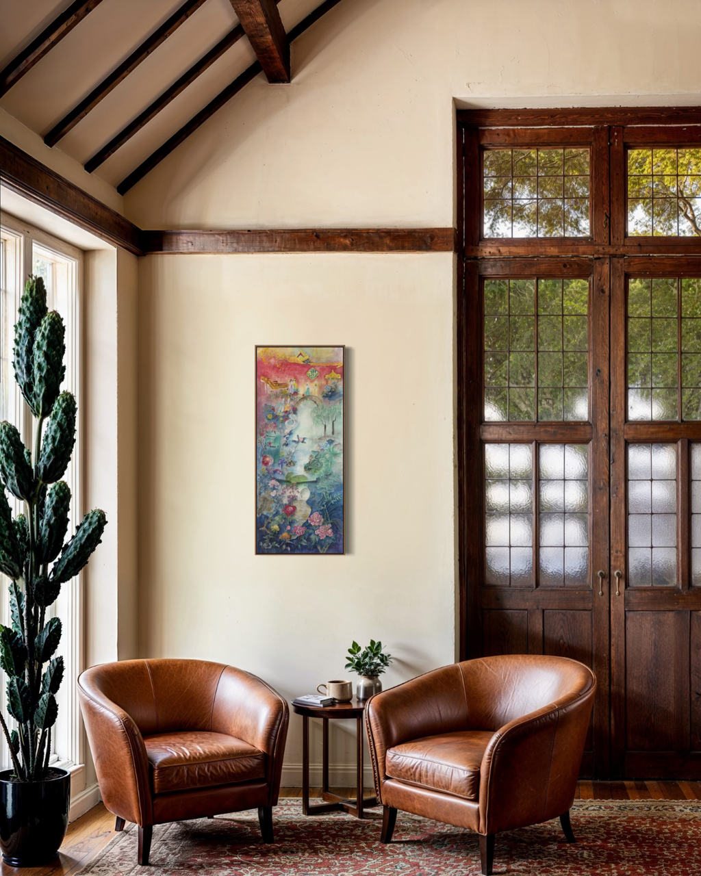 A tall, narrow abstract painting with vibrant pink, yellow, blue, and green tones hangs on a beige wall in a rustic room with two brown leather armchairs, a small side table, and dark wood double doors.